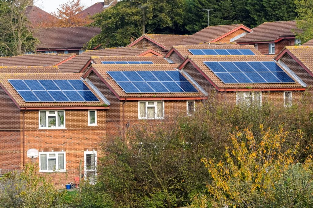 row of terrace red brick UK houses, all with solar panels on the roof