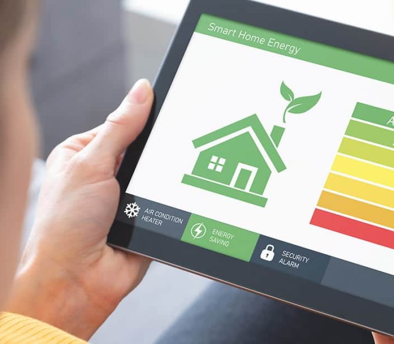 Woman holding a tablet with a home graphic and energy efficiency scale on the screen