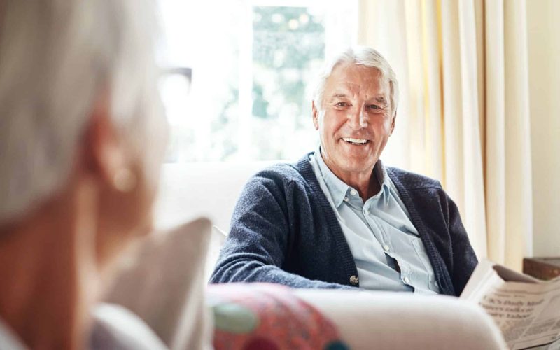 Older couple enjoying a relaxed conversation at home, reflecting the importance of ageing housing funding for comfort and independence