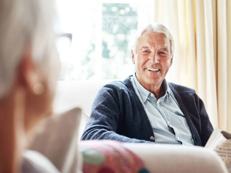 Older couple enjoying a relaxed conversation at home, reflecting the importance of ageing housing funding for comfort and independence