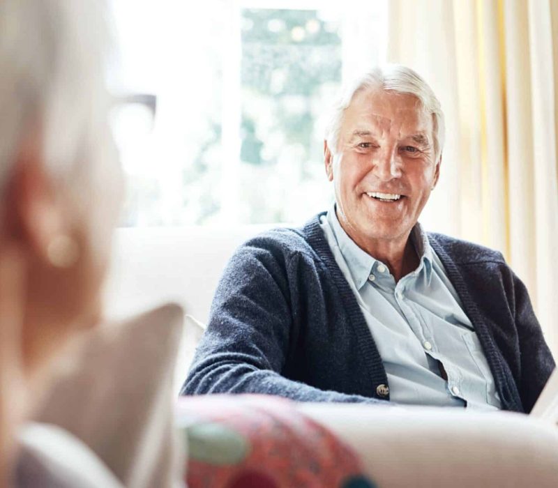 Older couple enjoying a relaxed conversation at home, reflecting the importance of ageing housing funding for comfort and independence