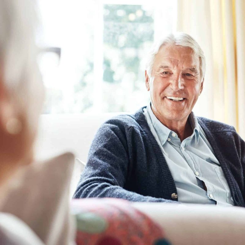 Older couple enjoying a relaxed conversation at home, reflecting the importance of ageing housing funding for comfort and independence