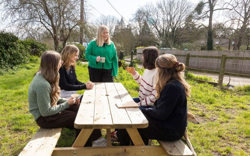 Team members sat outside on a picnic bench, sharing smiles